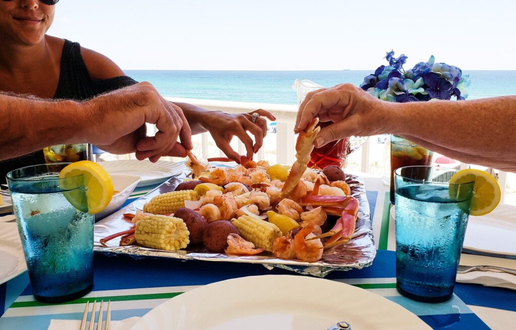 Family fun on beach vacation eating boiled seafood on deck overlooking beach landscape and ocean.