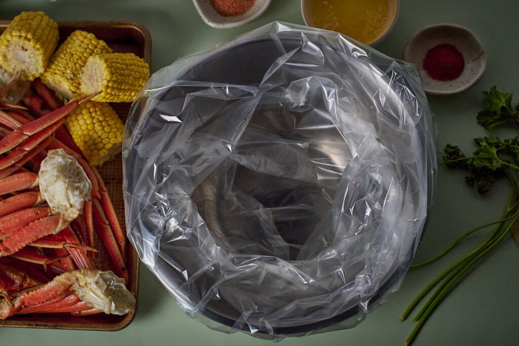 uncooked seafood boil and empty oven bag in bowl.