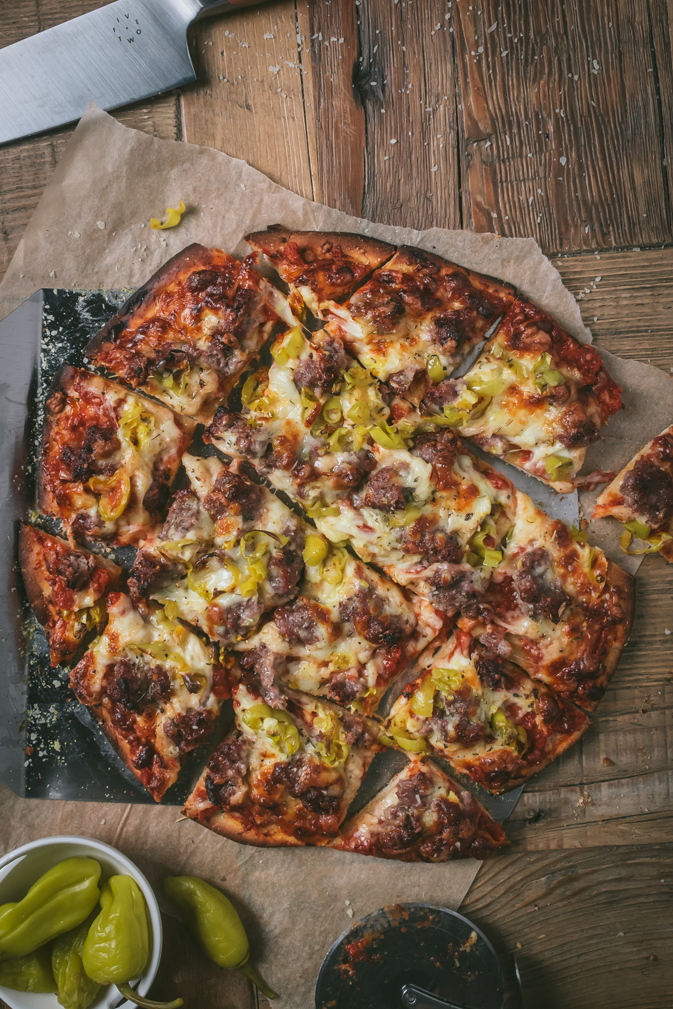 Sliced Thin Crust Sausage Pizza on parchment paper.